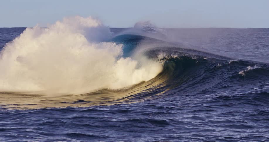 Wave in the ocean with a spray of water being blown by the wind creating an arch