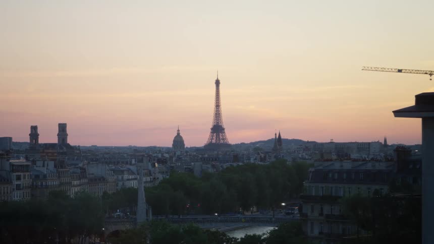 Panorama of a metropolis with the eiffel tower highlighted against an orange sky and shades of purple