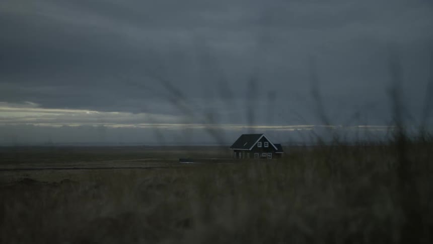Lonely house in a vast open landscape under a gloomy sky