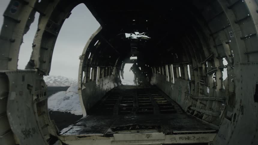 Abandoned airplane fuselage with its structure exposed and without seats against a backdrop of a snowy landscape