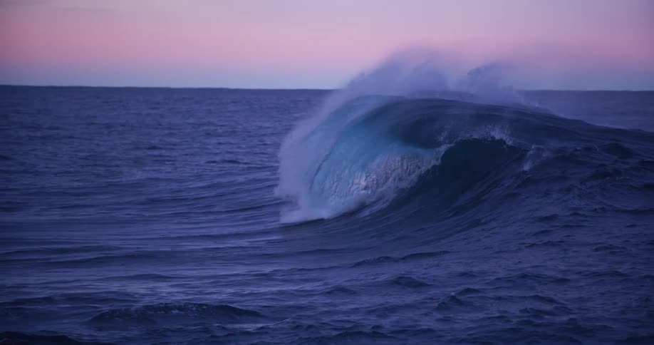 A wave moves along the ocean and crashes