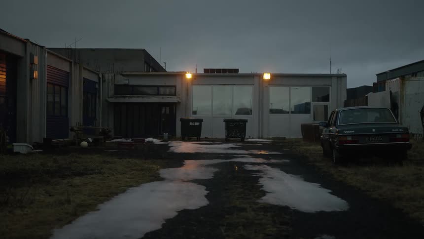 Ice melts on a driveway in front of a building with shining outside security lights