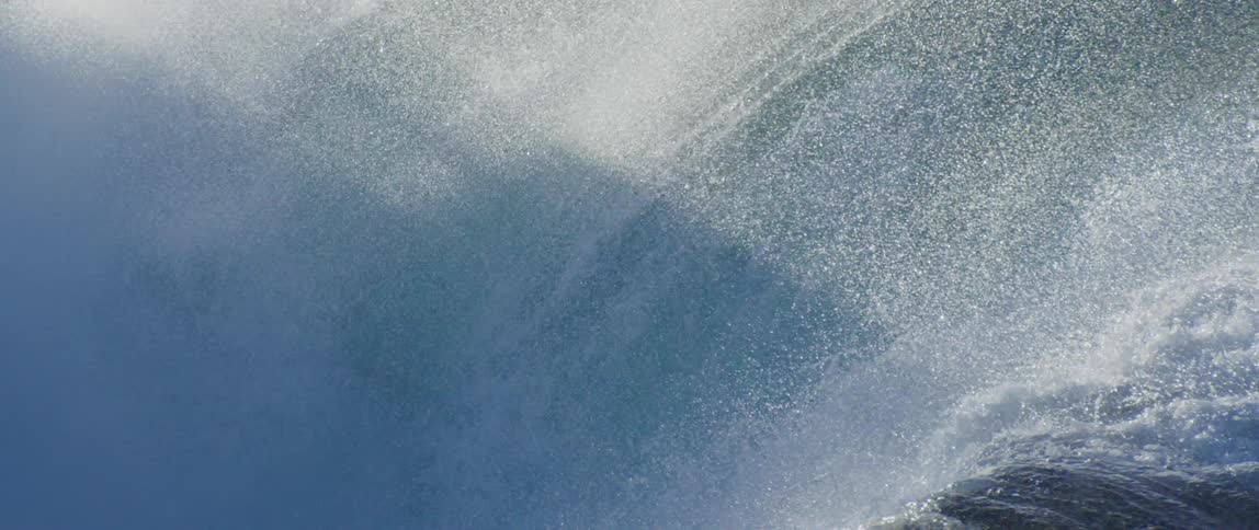 The inside of a wave as it crests and sprays water all around