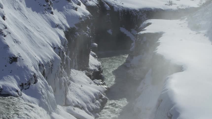 Waterfall in snowcovered mountains that gives access to a narrow river
