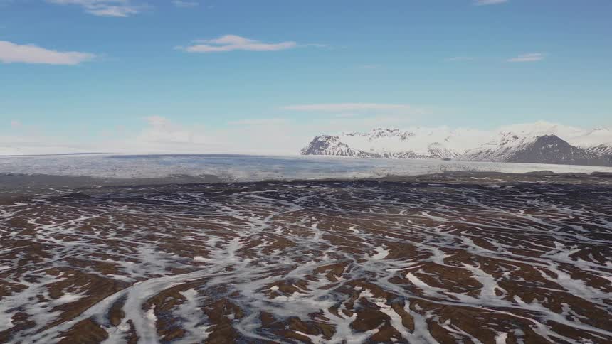 Panorama of a landscape with the ground and mountains covered in snow and a lake in the background