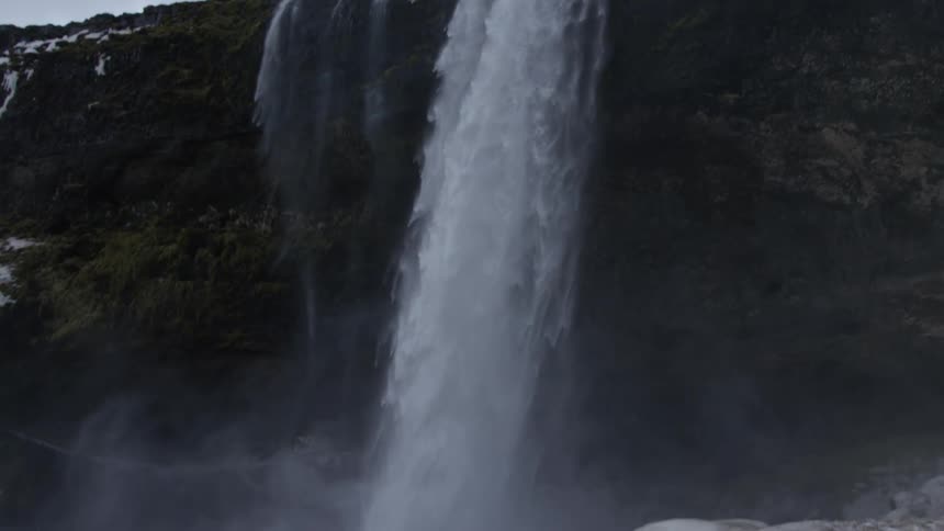 Waterfall free falling heavily from a cliff on a cloudy day