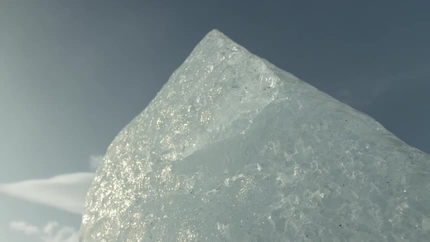 Translucent crystal ice with intricate internal textures against a clear blue sky