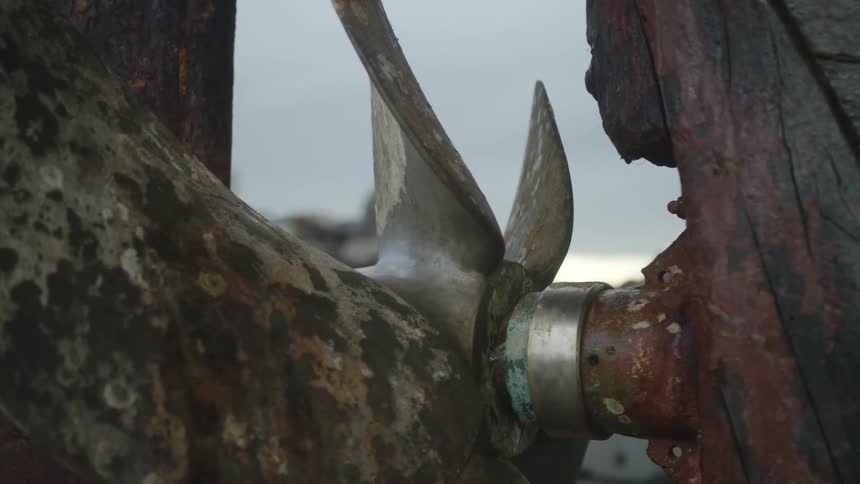 A boats metal propeller attached to a rusting structure