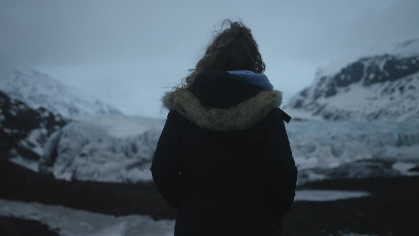 A woman is standing in front of the mountains