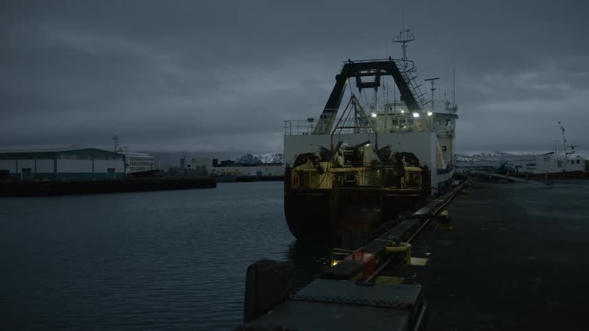 Industrial ship docked in a port on a dark and cloudy day