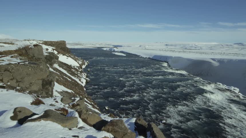 Landscape of snowcovered mountains on the banks of a vast flowing river