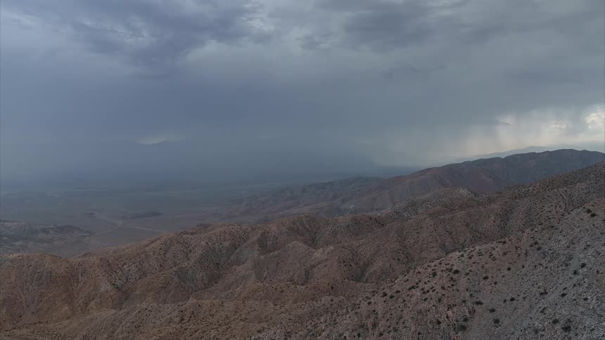 Vast arid landscape with rocky uneven terrain under a stormy sky