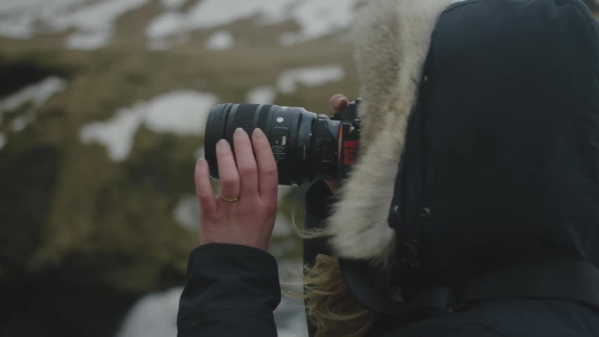 Woman holding a camera preparing to take a photo in a natural and snowy environment