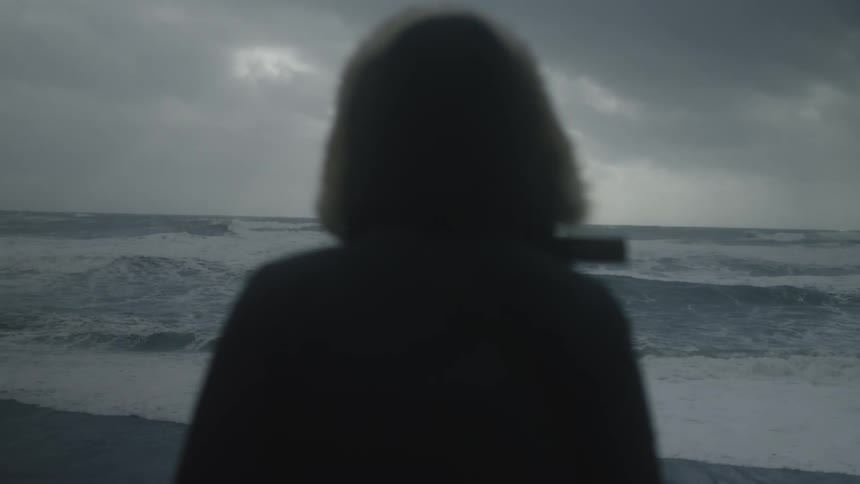 A person is watching the rough waters on the beach