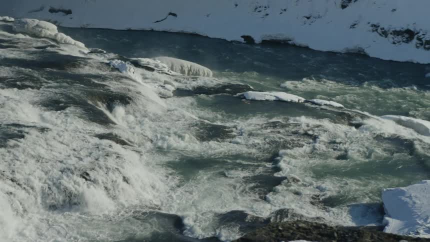 Turbulent river with fast flowing water surrounded by snowcovered banks