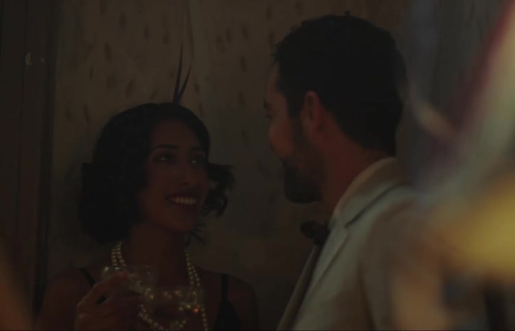 A couple laugh and drink at a house party