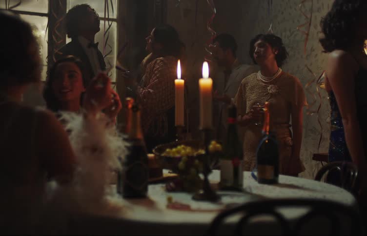 People gathered around a table with candles and food in a dimly lit room