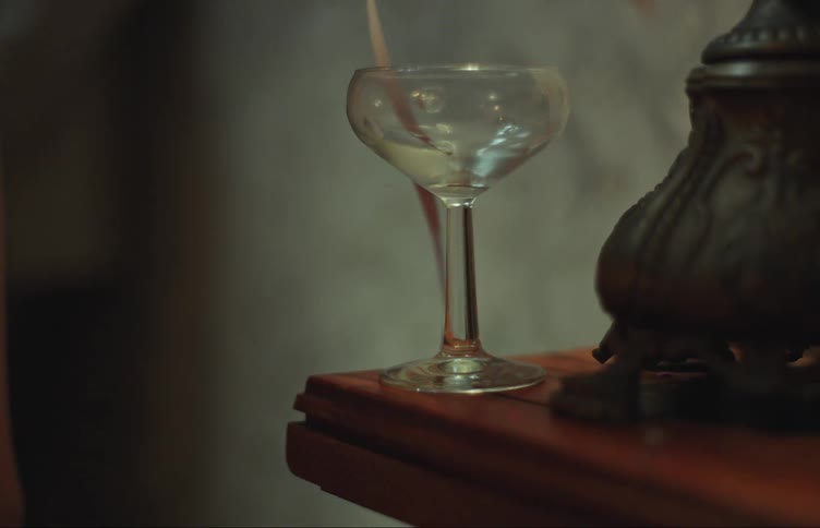 Womans hand placing a crystal cocktail glass on a wooden countertop
