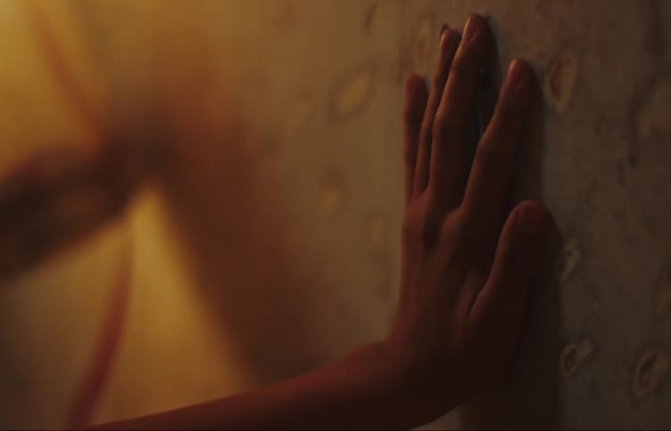 A human hand touching a wall in an environment with orange tones
