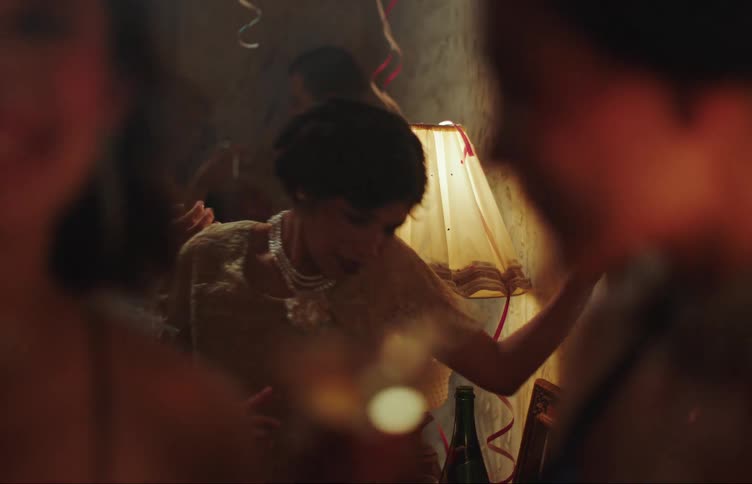 People in a dimly lit room with cocktails in their hands at a party