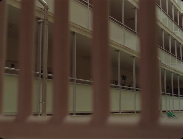 A multistory building with drain pipes seen through a fence