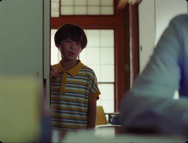 Boy in the doorway of a room and a man closing the door in front of him