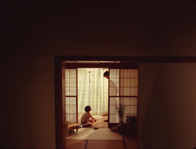 View of a mirror with a man sitting together with his son in the living room and playing