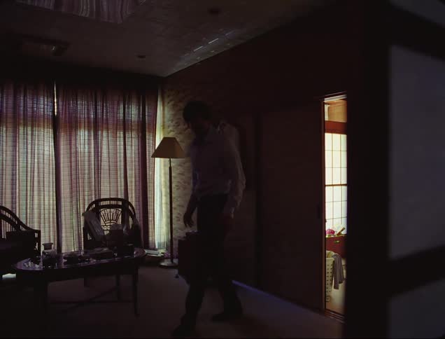 Man carefully entering a house with low lighting and getting scared