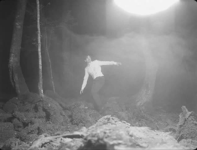 Man in a forest at night scared by abstract lights passing by