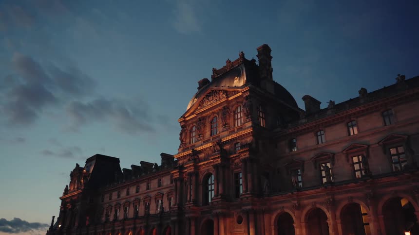 Outdoor lighting illuminates the detail rich facade of a large landmark building at night in Paris