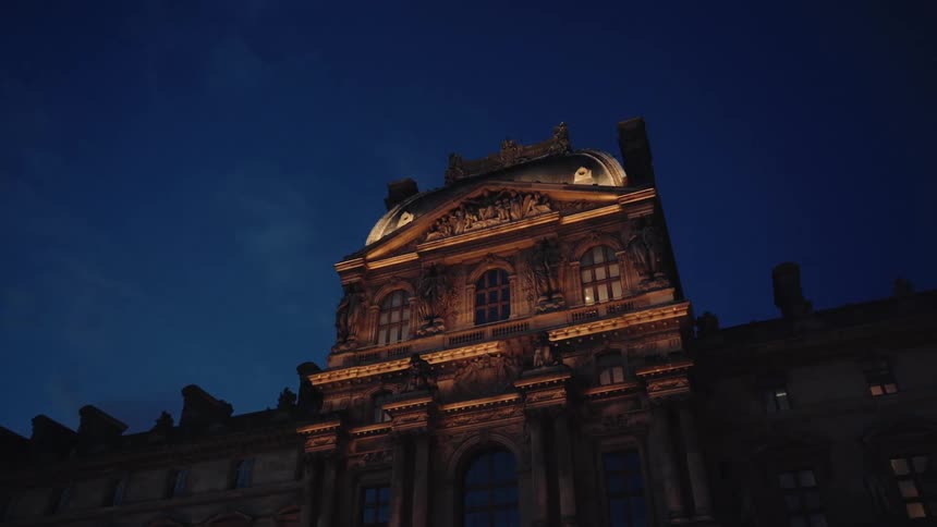 Louvre square with illuminated buildings around it against the blue night sky in Paris