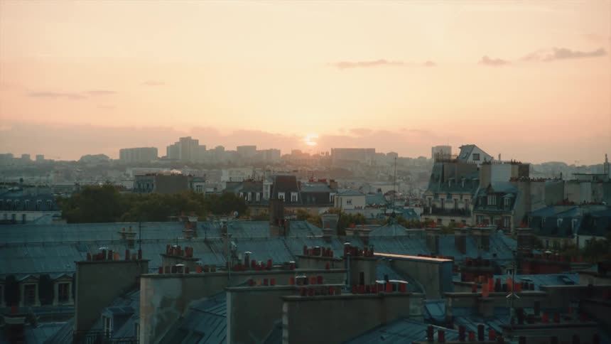 The sun rises over a dense city on a summer day in Paris