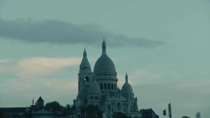Sacrcur basilica with its white domes standing out against a cloudy sky at dawn in Paris