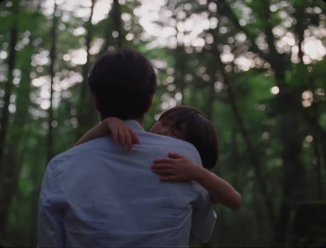 Father carries his sleepy child through the woods