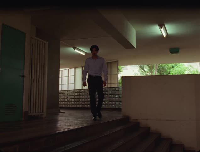 Father walking across a lobby towards his son who is sitting on the stairs of a building