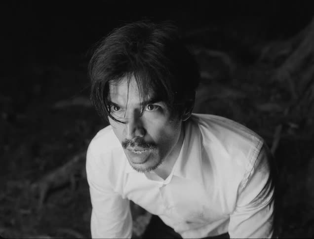 Portrait of a frightened man with a light appearing in the middle of a forest at night