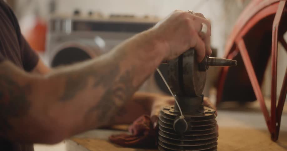 Male mechanic puts parts of machine together at workbench in the workshop
