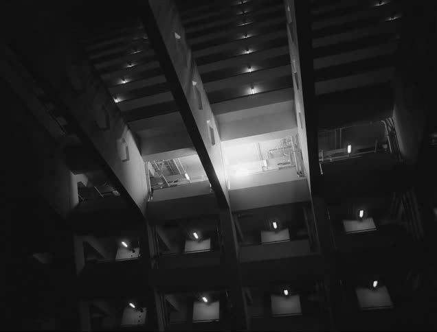 A monochrome view of the interior of a multistory building balconies and staircases with strong geometric patterns