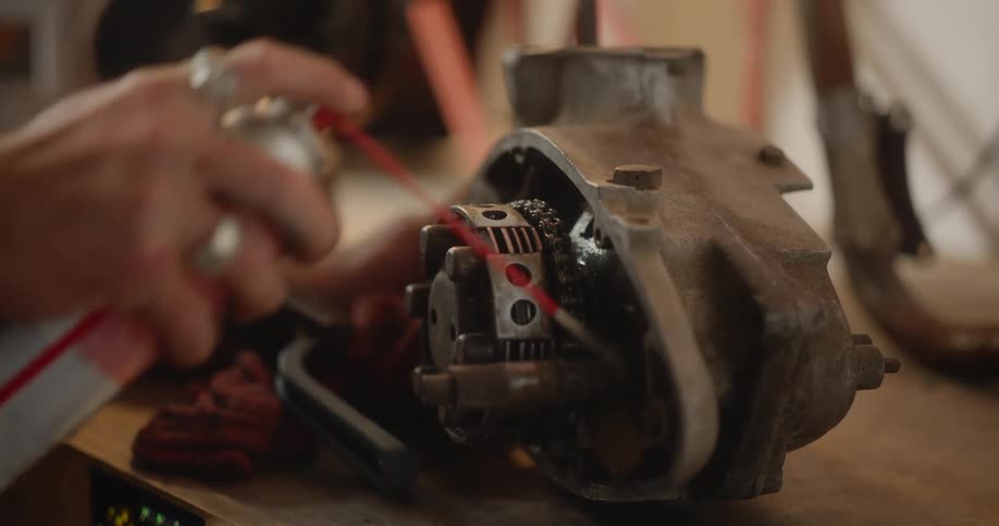 Hand spraying an automotive part on a wooden workbench