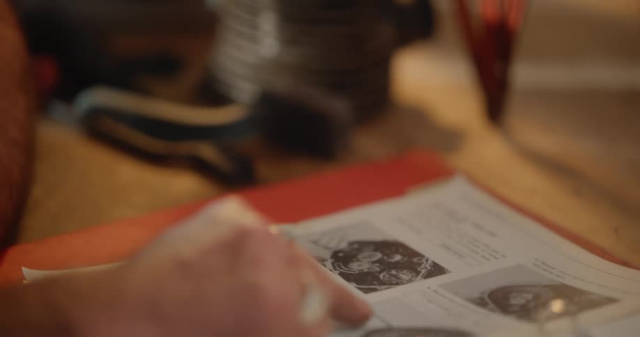Man sitting at a workbench consults a vehicle repair manual