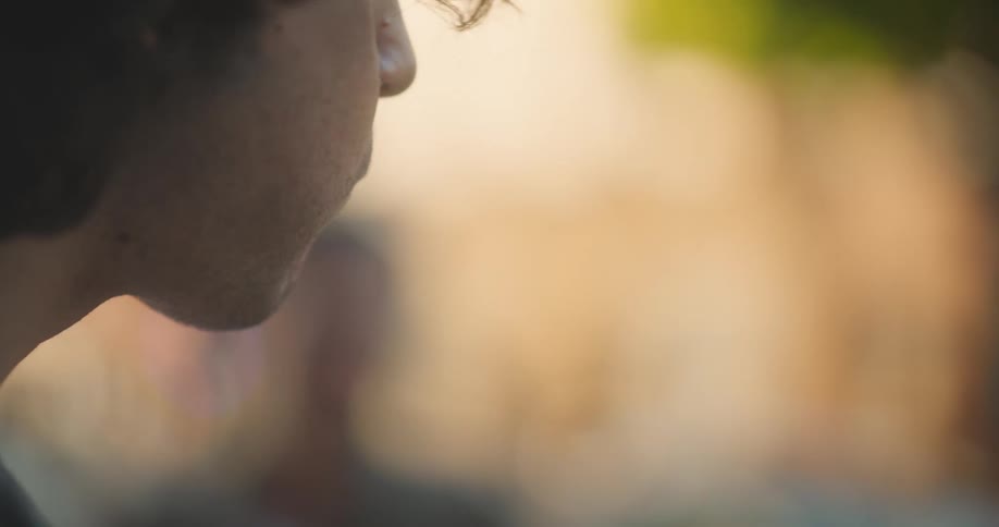 A man smiles while eating a hamburger outdoors