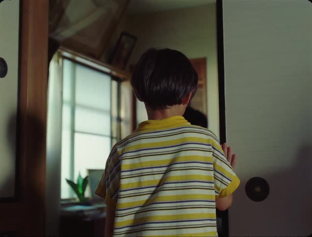Rear view of a boy looking out the door and a man closing the door in his face inside the house