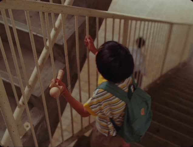 Boy walking up the stairs and a man in the background watching