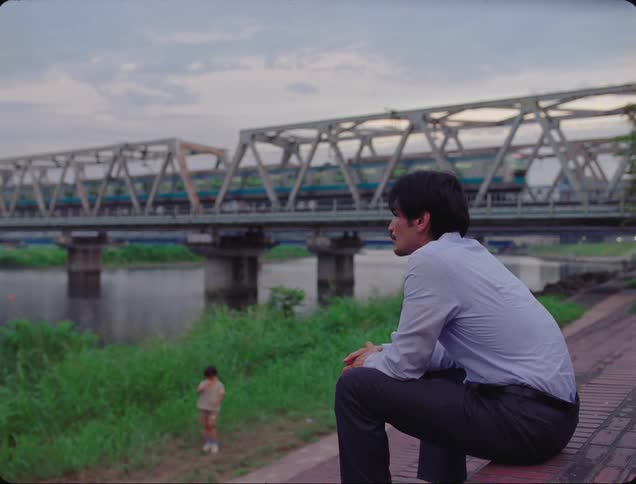 The train passes a child playing in the grass