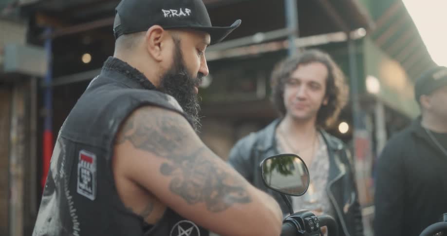 A group of biker friends drinking beer and talking to each other standing around their bicycles in the city