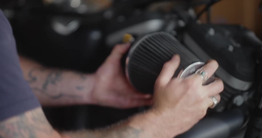 A mechanic attaches a new part to a motorcycle
