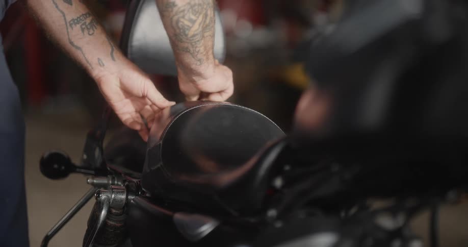 A male mechanic installs a seat cushion on a motorcycle in a shop