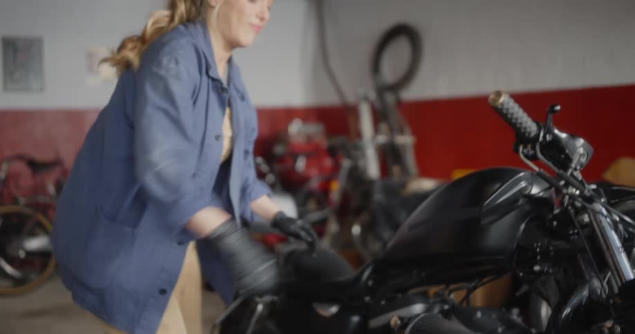 Blonde female mechanic using a screwdriver on a motorcycle and testing the throttle handlebars