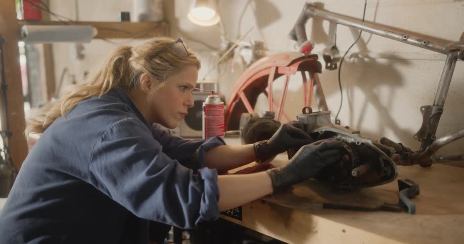 Female mechanic concentrating on an auto part