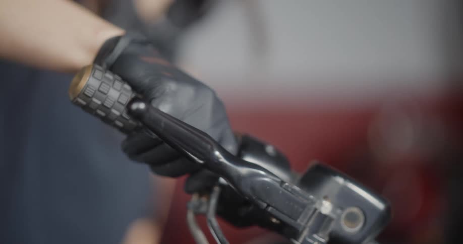A persons hand wearing a black glove grips the throttle of a motorcycle
